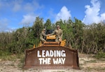 Two U.S. Air Force Airmen assigned to the 240th Civil Engineer Flight, Colorado Air National Guard pose on top of heavy machinery while deployed to the U.S. Indo-Pacific region during 2025. The 240 CEF completed a six-month deployment throughout various locations in the region, where they planned and rehabilitated key infrastructure. (courtesy photo)