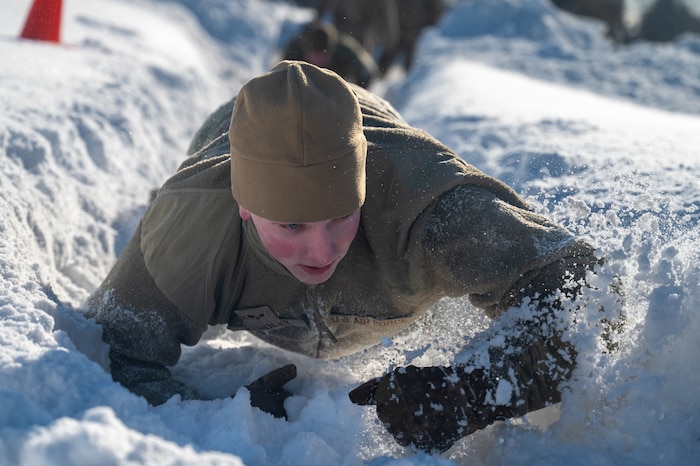 U.S. Air Force Senior Airman Luke Studley, an Airman Leadership School student, low crawls through the snow during the Combat Fitness Experience at the Elmendorf Professional Military Education Center on Joint Base Elmendorf-Richardson, Alaska, March 9, 2026. Beyond the physical exertion, CFE serves as a critical leadership exercise, forcing students to communicate under pressure and synchronize as a flight to achieve mission success. (U.S. Air Force photo by Airman 1st Class Theodore Gowdy)