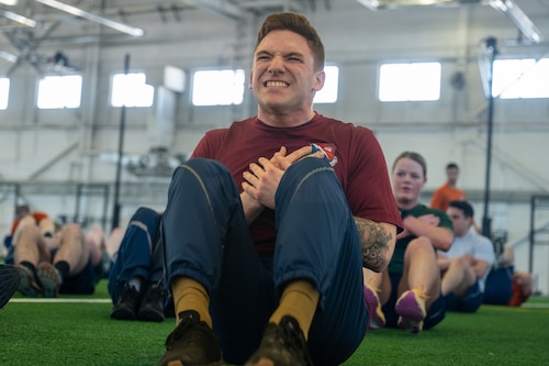 U.S. Air Force Senior Airman Sckylar Huffman, an Airman Leadership School student, performs sit-ups during the Omega physical training event at Hangar 5 on Joint Base Elmendorf-Richardson, Alaska, March 25, 2026. By emphasizing high-intensity, equipment-free movements, the training ensures that future leaders maintain a high level of physical readiness regardless of their operational environment or mission constraints. (U.S. Air Force photo by Airman 1st Class Theodore Gowdy)