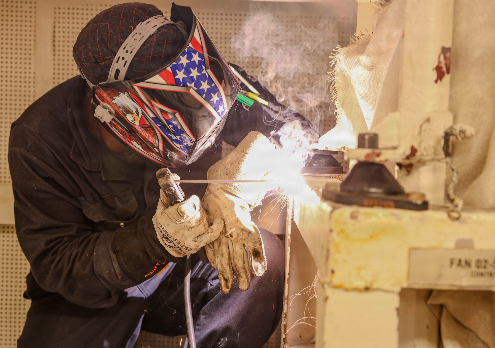Hull Maintenance Technician 2nd Class Christian Deang, assigned to Southwest Regional Maintenance Center, welds a fan unit bracket aboard Whidbey Island-class dock landing ship USS Ashland (LSD 48) as part of ship wartime repair and maintenance exercise (SWARMEX) in Cebu, Philippines, March 25, 2026. SWARMEX is designed to rehearse coordination and execution of ship damage repair from forward locations within the Indo-Pacific region, strengthening ties with the skilled workforce within allied and partner countries. (U.S. Navy photo by Mass Communication Specialist Seaman Maliq J. Martin)