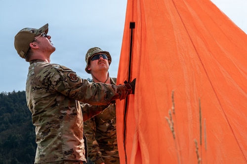 Two people putting up a bright orange field marker