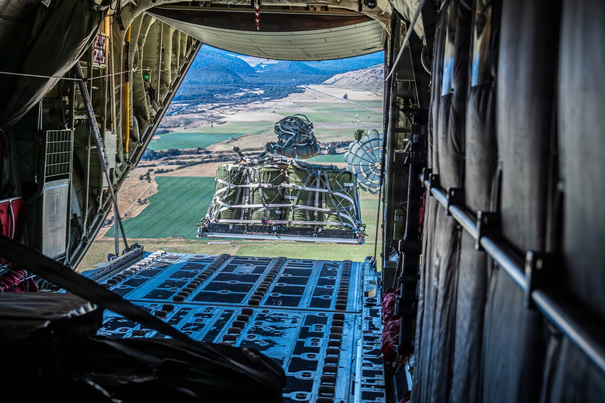 A large cargo bundle falling out of the ramp of an aircraft