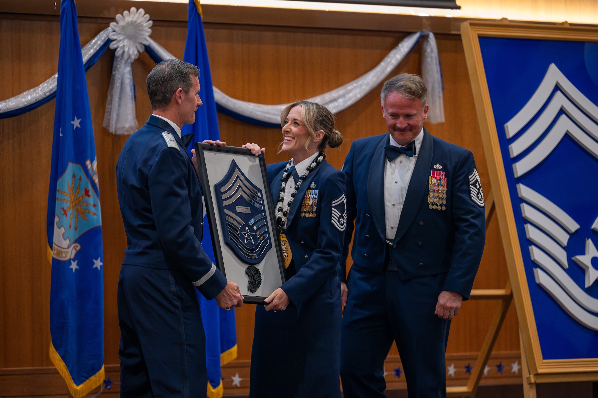 U.S. Air Force Brig. Gen. John Gallemore, left, 18th Wing commander and Chief Master Sgt. William Cupp, right, 18th Wing command chief, present a chief master sergeant plaque to Senior Master Sgt. Cassidy L. Wong, 718th Force Support Squadron superintendent of postal operations, during a chief induction ceremony at Kadena Air Base, Japan, March 28, 2026. The rank of chief master sergeant is the highest enlisted rank in the Air Force, with only one percent of the enlisted force structure reaching it. (U.S. Air Force photo by Airman 1st Class Francisco Huerta)