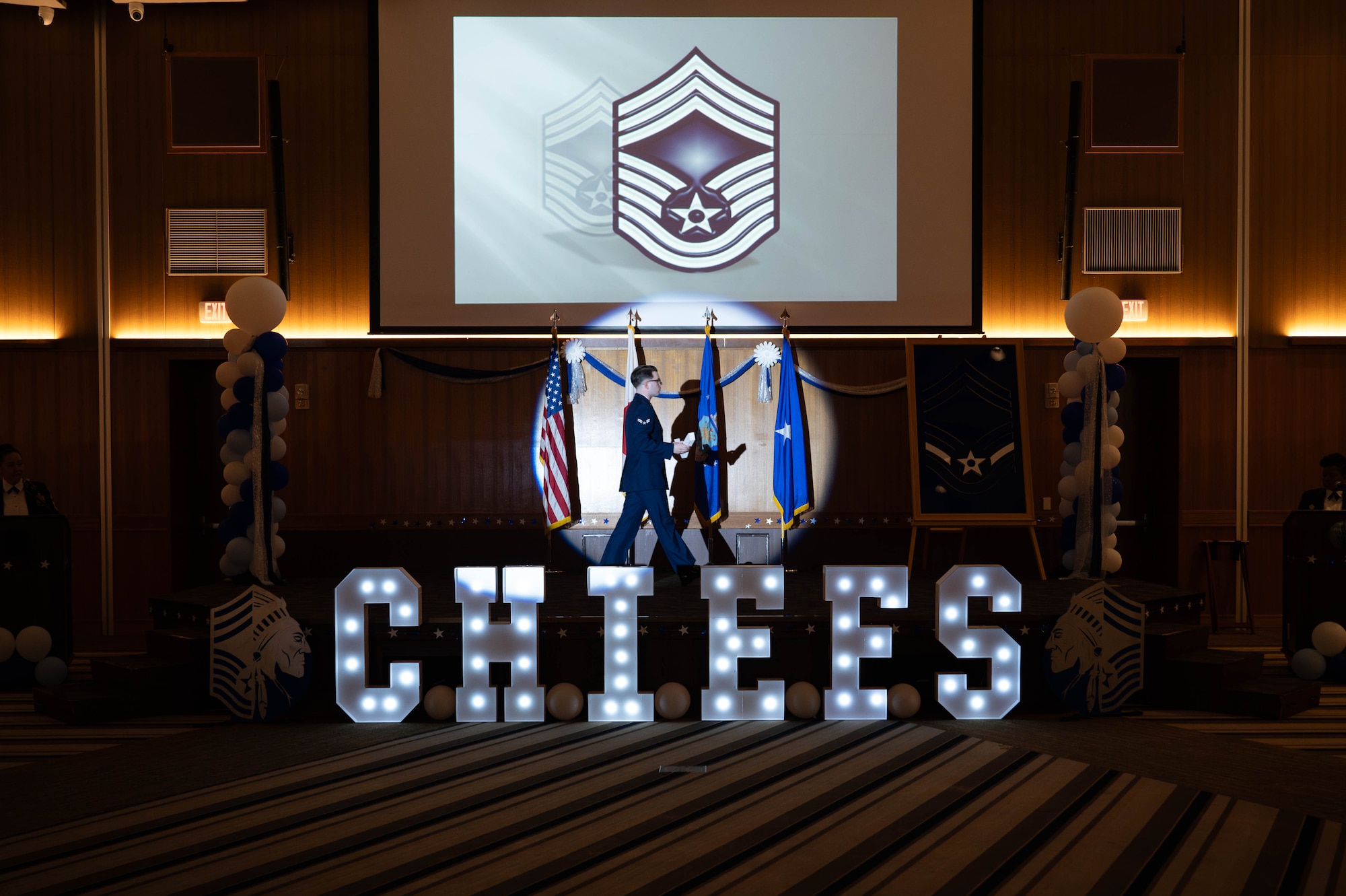 U.S. Air Force Airman 1st Class Hunter Back, 718th Force Support Squadron postal clerk, walks across stage to place the chevron for the airman 1st class rank insignia during a chief induction ceremony at Kadena Air Base, Japan, March 28, 2026. The stripe ceremony is used to signify all the ranks the inductees surpassed on their path to their new rank. (U.S. Air Force photo by Airman 1st Class Nathaniel Jackson)
