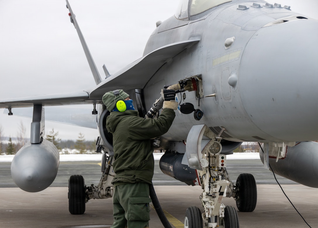 A Finnish airman with Fighter Squadron 11, Lapland Air Wing, connects a pressure-locking nozzle into a Finnish F/A-18 Hornet aircraft at a forward arming and refueling point at Rovaniemi Air Base, Finland, March 17, 2026. U.S. Marines with MWSS-273 simulated refueling Finnish F/A-18s with Fighter Squadron 11, Lapland Air Wing, during air operations for exercise Cold Response 26. A key component of NATO's enhanced vigilance activity Arctic Sentry, exercise Cold Response 26 is a Norwegian-led winter military exercise designed to enhance collective defense capabilities and ensure U.S. readiness to rapidly deploy and seamlessly operate alongside NATO Allies in challenging arctic conditions. (U.S. Marine Corps photo by Lance Cpl. Donovan Pimentel)
