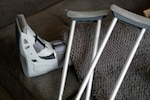 An orthopedic boot with two crutches leaning back against it.