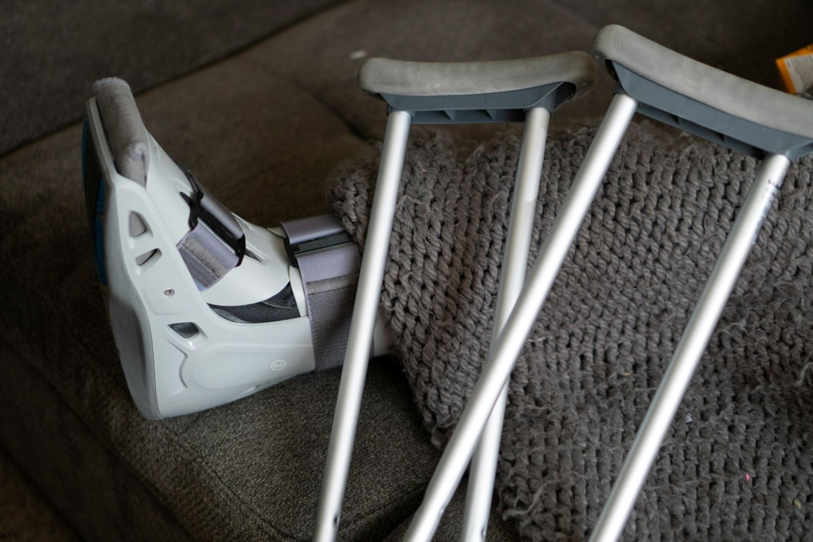 An orthopedic boot with two crutches leaning back against it.