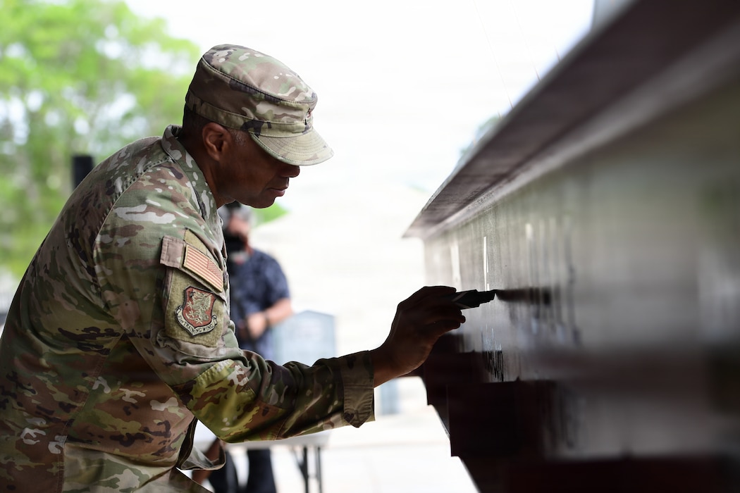 A man in military uniform signs a steel beam.