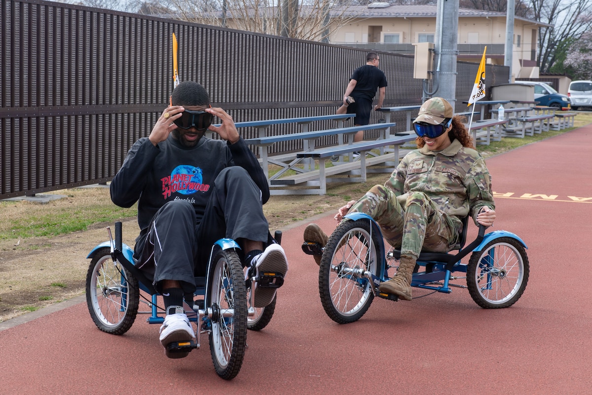 Two people wearing goggles ride bikes.