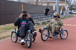 Two people wearing goggles ride bikes.