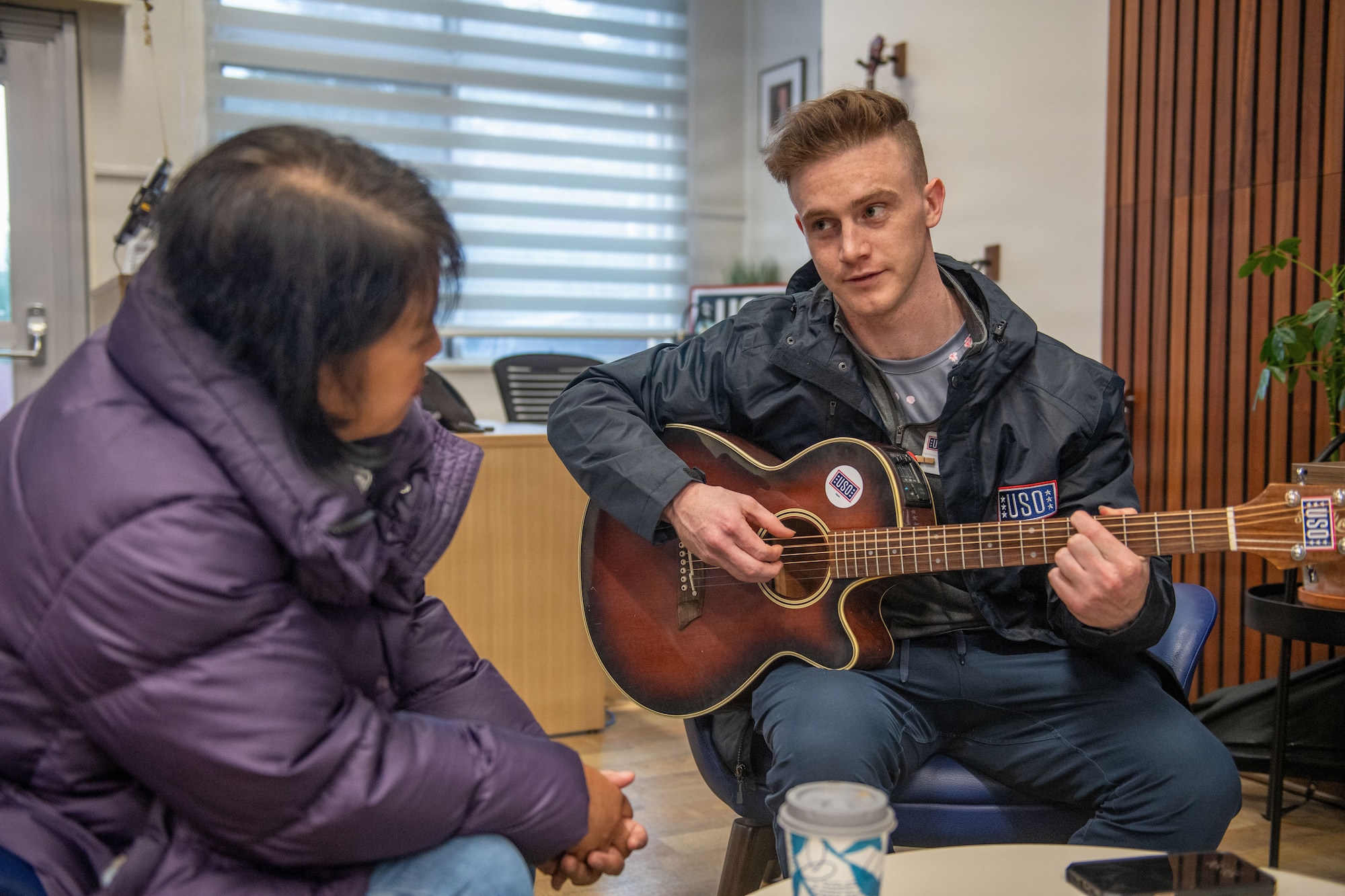 A man plays a guitar to a woman.