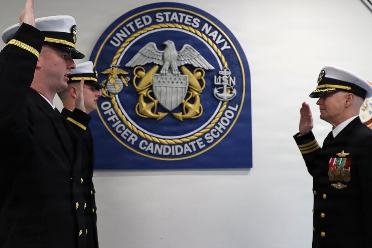 251121-N-N0443-1001 Cmdr. Eric Melvin, a U.S. Navy chaplain assigned to the USS Theodore Roosevelt (CVN 71), administers the oath of office to his sons, Ensign Zachary Melvin and Ensign Samuel Melvin, during a commissioning ceremony at Officer Candidate School (OCS), in Newport, Rhode Island. The Melvin brothers were commissioned together privately before the ceremony, with their father presiding over the oath.