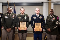 U.S. Army Sgt. Derek Tucker and Spc. Trevor Lock, military police officers with the 105th Military Police Company, 102nd Military Police Battalion, receive gifts for first place at the New York Army National Guard Best Warrior Competition 2026 during an awards ceremony at Camp Smith Training Site, Cortlandt Manor, New York, March 26, 2026.