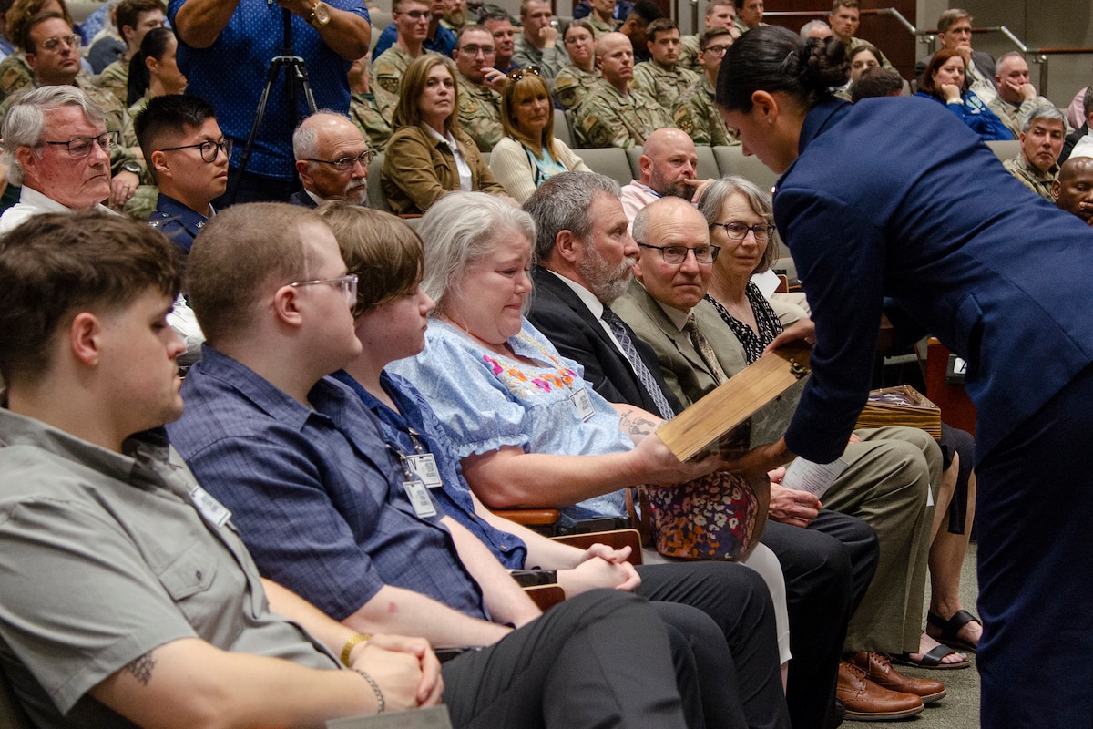 Jennifer Paynter (center) flanked by her sons Benjamin, Luke and Samuel, is presented with an engraved shadow box containing an American flag that was flown above the Air Force Technical Applications Center in memory of her husband, Lt. Col. (ret.) David Paynter, who passed away while actively serving at AFTAC as a federal civilian.  (U.S. Air Force photo by Susan A. Romano)