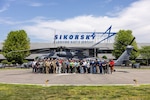 A group stands for a photo in front of a helicopter