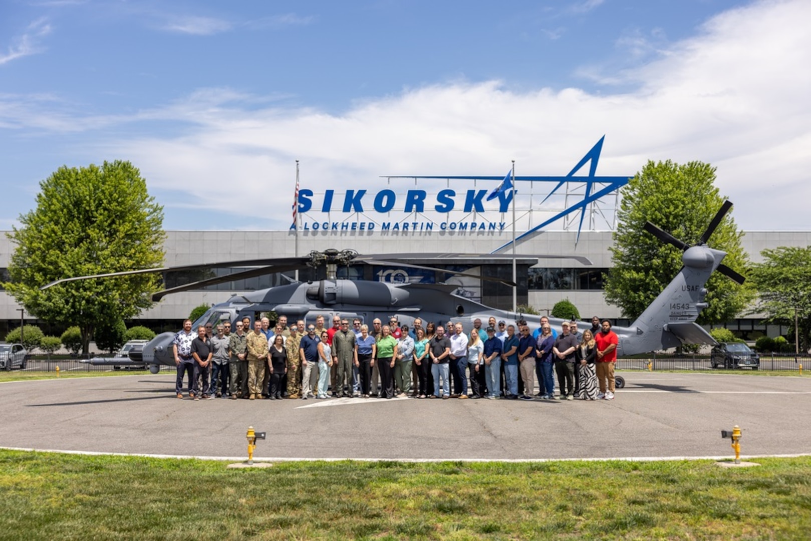 A group stands for a photo in front of a helicopter