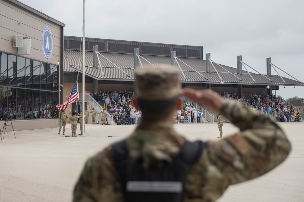 A U.S. Air Force Basic Military Training trainee salutes the American flag during the retreat portion of the Coin and Retreat Ceremony at Joint Base San Antonio-Lackland, Texas, April 1, 2026. Following the coin presentation, the retreat portion of the ceremony includes the American flag being lowered and folded as the National Anthem is played. (U.S. Air Force photo by Airman 1st Class Emma Wright)
