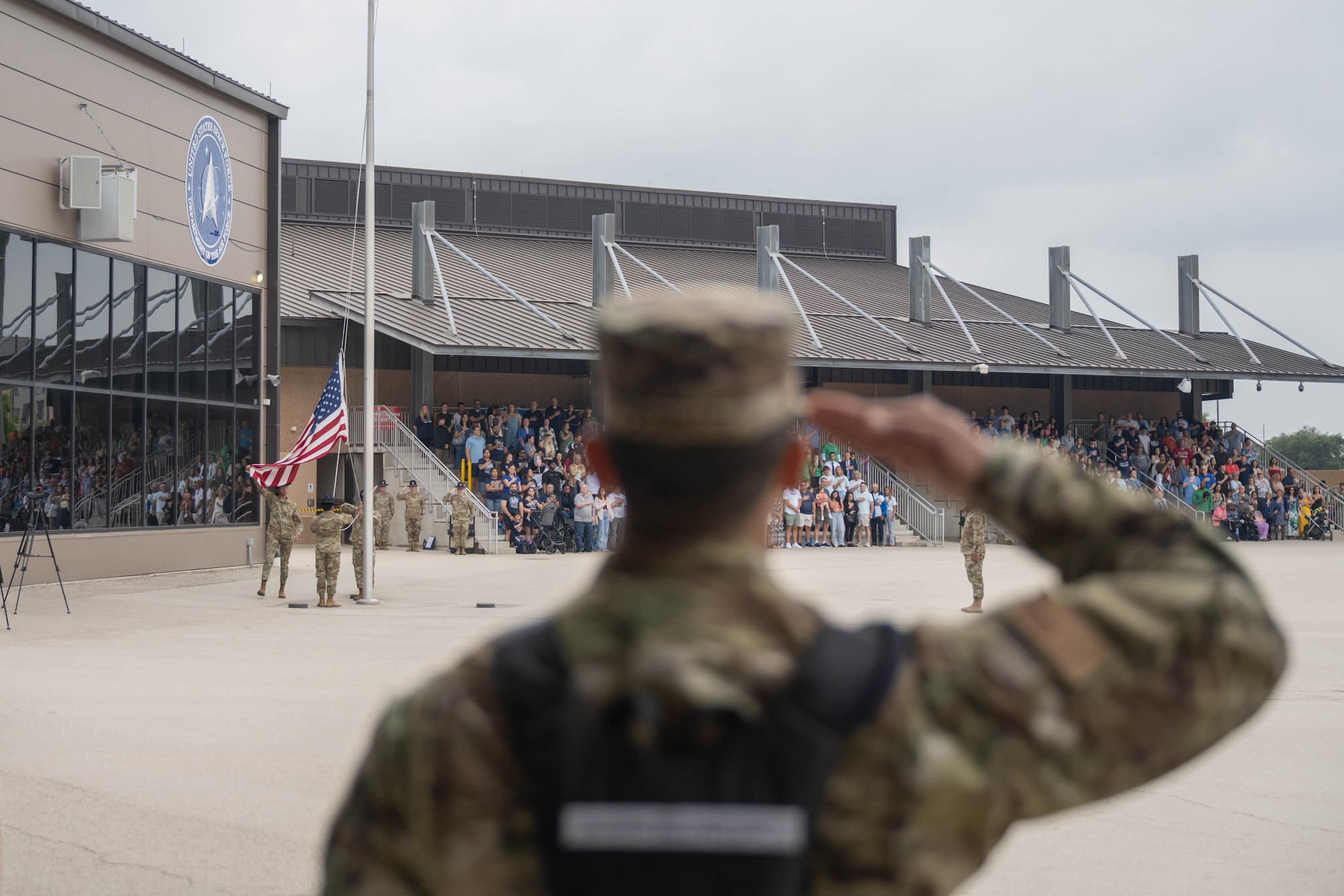 A U.S. Air Force Basic Military Training trainee salutes the American flag during the retreat portion of the Coin and Retreat Ceremony at Joint Base San Antonio-Lackland, Texas, April 1, 2026. Following the coin presentation, the retreat portion of the ceremony includes the American flag being lowered and folded as the National Anthem is played. (U.S. Air Force photo by Airman 1st Class Emma Wright)