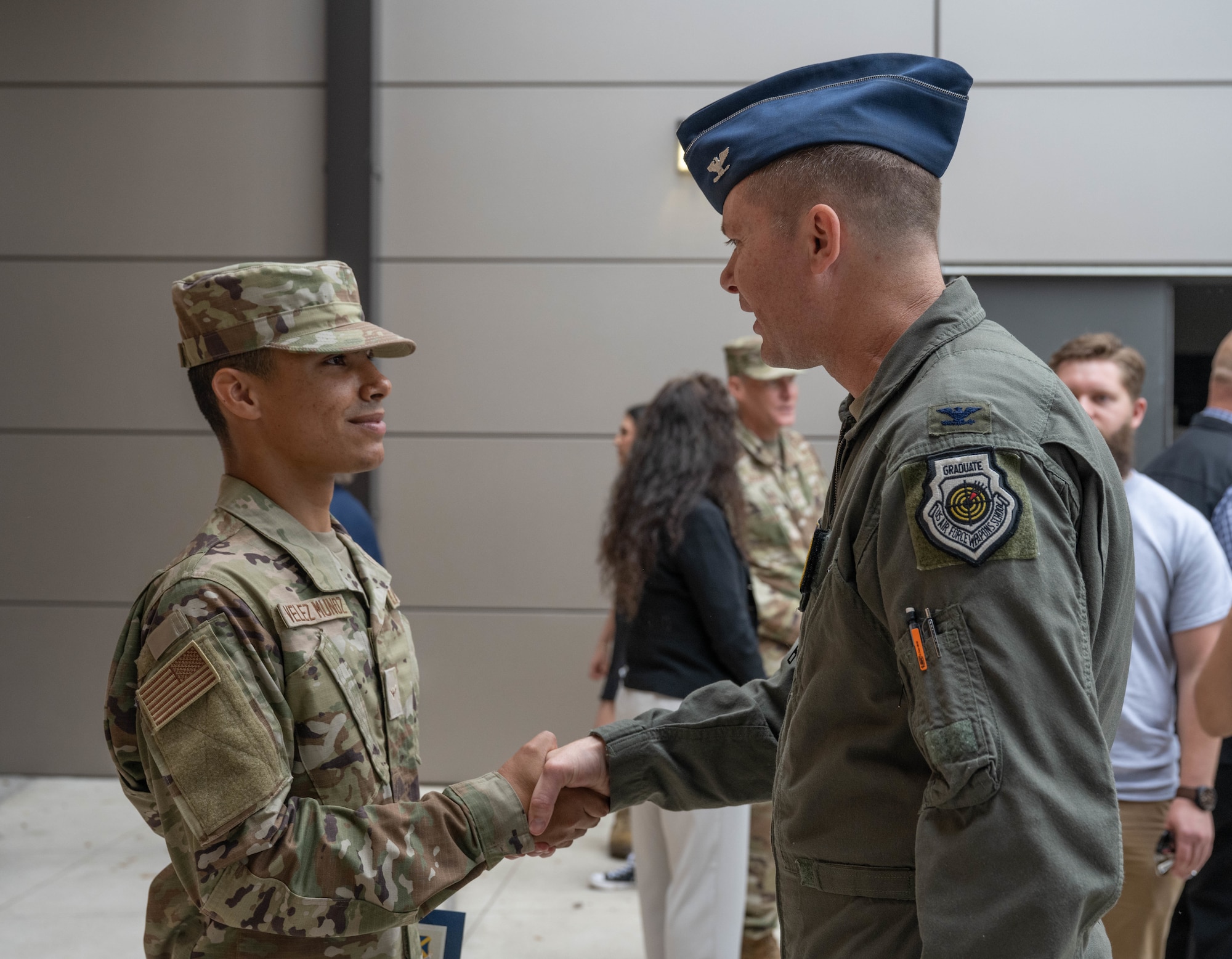 U.S. Air Force Col. Richard Kind, 97th Air Mobility Wing (AMW) commander, right, coins a U.S. Air Force Airman who was awarded top graduate of his Basic Military Training graduating class at Joint Base San Antonio-Lackland, Texas, April 1, 2026. The top graduate is selected using a point system that considers physical training scores, academic performance, dorm and uniform inspections, as well as leadership and disciplinary records. (U.S. Air Force photo by Airman 1st Class Emma Wright)