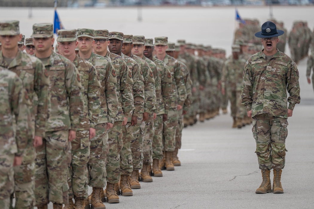 U.S. Air Force Basic Military Training trainees stand at attention in front of a military training instructor (MTI) during the Coin and Retreat Ceremony at Joint Base San Antonio-Lackland, Texas, April 1, 2026. MTIs uphold their trainees to the highest standards in detail, bearing, discipline and drill excellence, all of which are displayed during the Coin and Retreat Ceremony. (U.S. Air Force photo by Airman 1st Class Emma Wright)