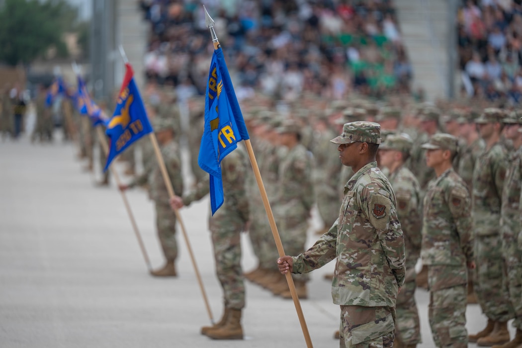 U.S. Air Force Basic Military Training trainees stand at parade rest during the Coin and Retreat Ceremony at Joint Base San Antonio-Lackland, Texas, April 1, 2026. Following the coin presentation and lowering of the flag, trainees sing the Air Force song and cite the Airman’s creed. (U.S. Air Force photo by Airman 1st Class Emma Wright)