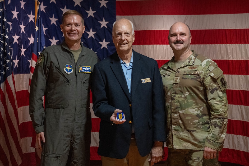U.S. Air Force Col. Richard Kind, 97th Air Mobility Wing (AMW) commander, left, and Chief Master Sgt. Jonny Adams, 97th AMW command chief, right, pose with David Shultz, American Heritage Foundation education/outreach program manager, at the American Heritage Museum at Joint Base San Antonio-Lackland, Texas, April 1, 2026. The command team coined Schultz for his contributions to the 2025 Altus Air Force Ball, highlighting the importance of community support in mission success. (U.S. Air Force photo by Airman 1st Class Emma Wright)