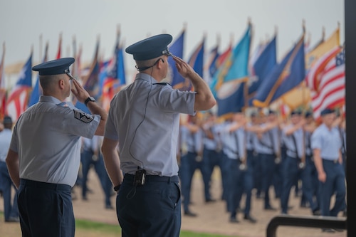 U.S. Air Force Col. Richard Kind, 97th Air Mobility Wing (AMW) commander, right, and Chief Master Sgt. Jonny Adams, 97th AMW command chief, left, salute the American flag during the pass in review portion of the parade at Joint Base San Antonio-Lackland, Texas, April 2, 2026.  Kind served as the reviewing official for the 737th Training Group’s graduation parade, the final of three graduation events marking the new Airmen’s transition into the next phase of their Air Force careers. (U.S. Air Force photo by Airman 1st Class Emma Wright)
