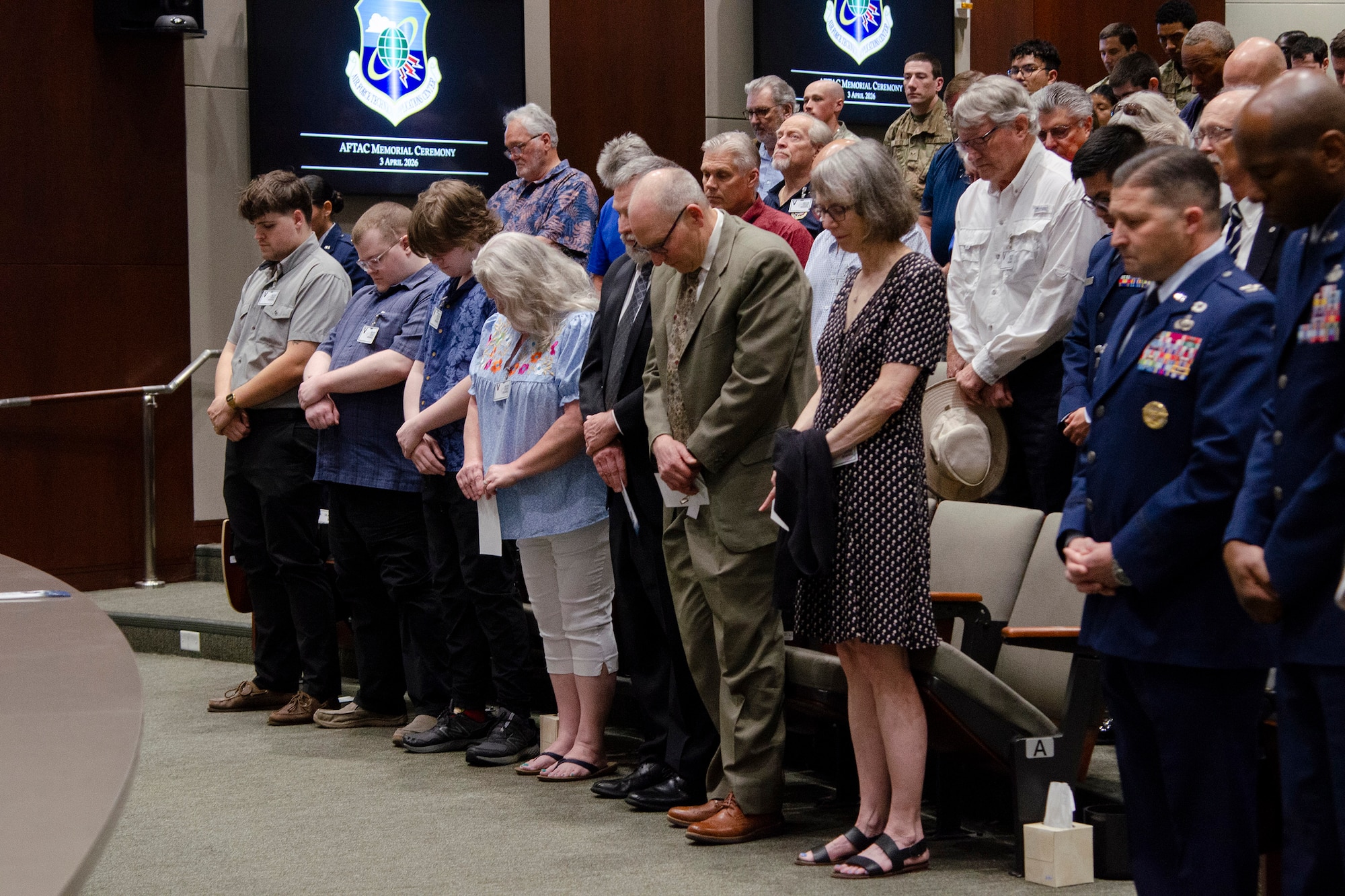 Family members of Dr. Gregory Wagner and Lt. Col. (ret.) David Paynter (front row, left), along with leadership and members of the Air Force Technical Applications Center, bow their heads during a moment of prayer during a ceremony April 3, 2026  that memorialized Wagner’s and Paynter’s federal service, both who passed away while actively serving the nation.  (U.S. Air Force photo by Susan A. Romano)