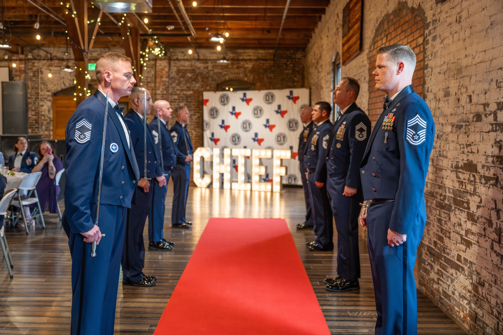 U.S. Air Force chief master sergeants assigned to Dyess Air Force Base prepare a saber cordon during a Chief Master Sergeant Induction Ceremony in Abilene, Texas, March 28, 2026. Walking through the saber archway symbolizes the inductees’ welcome into the highest enlisted tier. (U.S. Air Force photo by Airman 1st Class Caleb Schellenberg)
