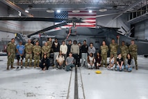 Airmen pose with foster teens in front of military helicopter
