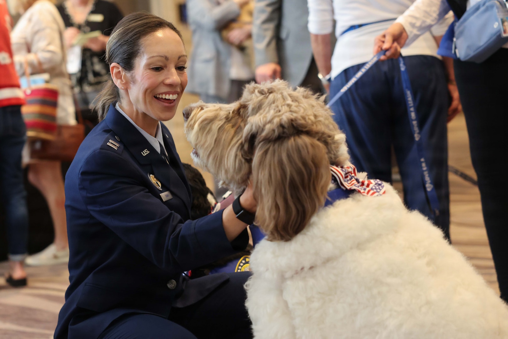 U.S. Air Force Capt. Montana Banks pets a dog from Love on a Leash, a therapy dog organization that provides certified therapy dogs for veterans and others in need, pose for a photo during the Defense POW/MIA Accounting Agency Family Member Update in San Diego, Ca., March 28, 2026