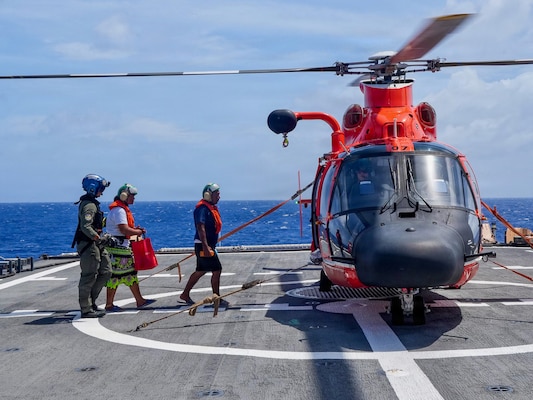 U.S. Coast Guard Petty Officer 3rd Class James Warguez, an aviation maintenance technician assigned to Air Station Barber’s Point, escorts members of a local family to a U.S. Coast Guard MH-65 Dolphin helicopter embarked on Legend-class cutter USCGC Midgett (WMSL 757) for further transport to Weno, Federated States of Micronesia, on April 6, 2026. The crew of Midgett rescued the family on April 6 after their 23-foot single-outboard skiff vessel went missing a week earlier in the waters of Chuuk State. U.S. Coast Guard missions in the Indo-Pacific focus on issues that directly support and advance our regional partners’ efforts to protect fish stocks and ensure the safety of life at sea, helping to ensure a secure and prosperous Indo-Pacific. (U.S. Coast Guard photo by Petty Officer 3rd Class Jennifer Nilson)