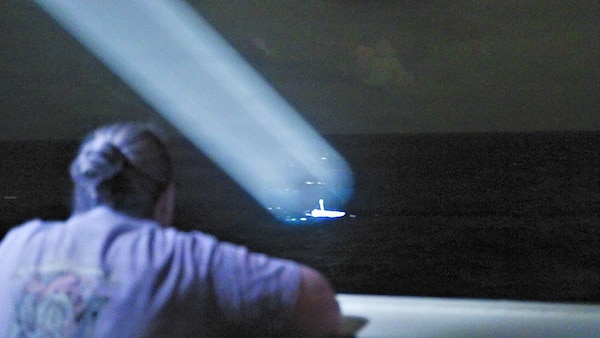U.S. Coast Guard Lt. Cmdr. Stephanie Jocis, operations officer aboard Legend-class cutter USCGC Midgett (WMSL 757), observes a 23-foot single-outboard skiff vessel, carrying three members of a missing family in the waters of Chuuk State, Federated States of Micronesia, in Midgett’s search light during the early hours of April 6, 2026. The crew of Midgett rescued the family after the vessel went missing on March 30 in the waters of Chuuk State. U.S. Coast Guard missions in the Indo-Pacific focus on issues directly supporting and advancing our regional partners’ efforts to protect fish stocks and ensure the safety of life at sea, ensuring a secure and prosperous Indo-Pacific. (U.S. Coast Guard photo by Seaman Lauren Taber)