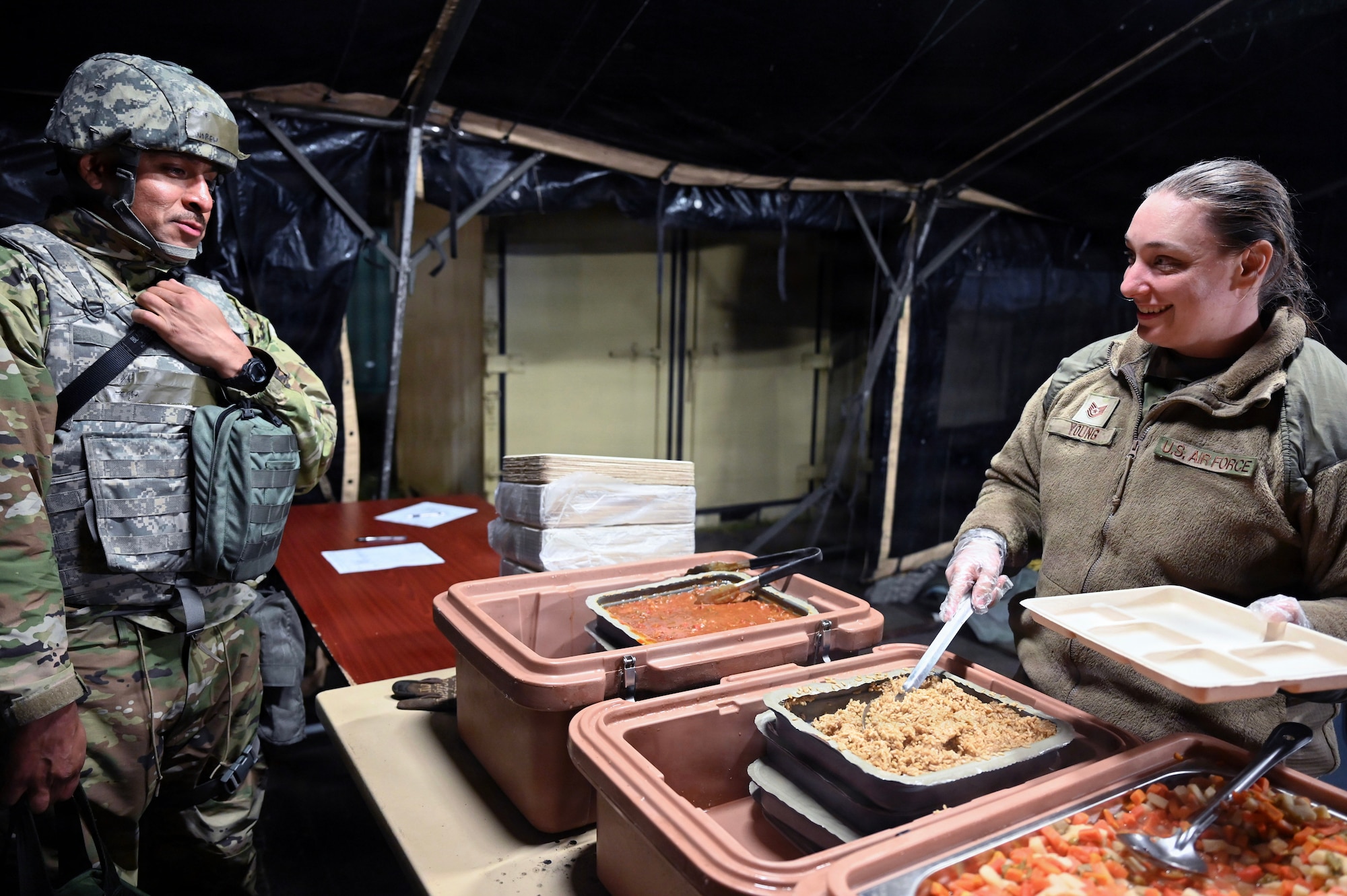 A military member serves food to another member
