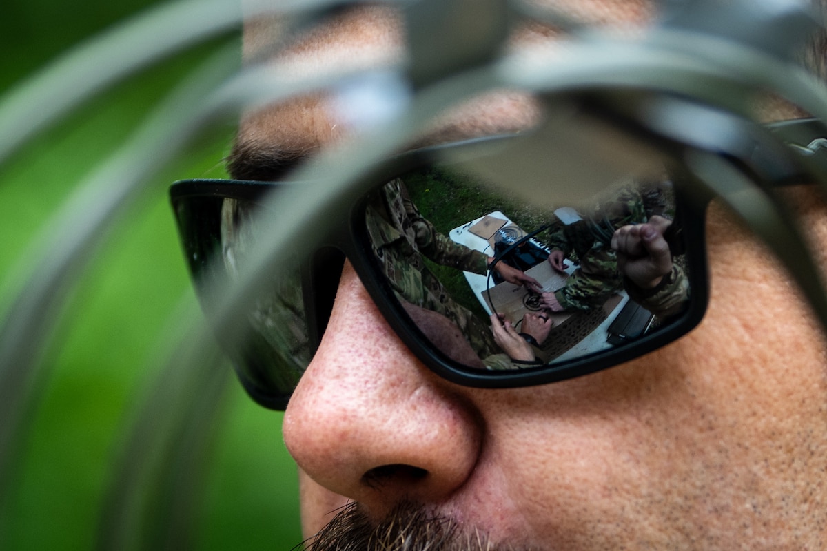 A person watches over a group of people wiring training explosives.