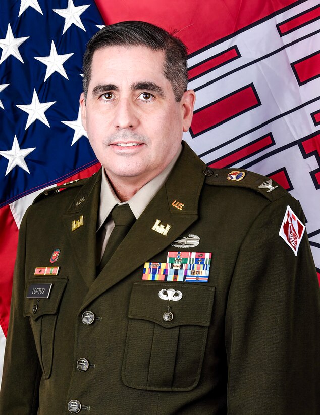 An Army officer in dress uniform poses for an official photo in front of the U.S. and U.S. Army Corps of Engineers flags