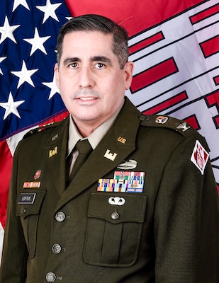 An Army officer in dress uniform poses for an official photo in front of the U.S. and U.S. Army Corps of Engineers flags