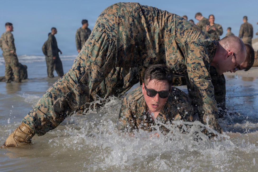 U.S. Marines with II Marine Expeditionary Force Support Battalion, participate in a
group exercise during a ruck-run at Onslow Beach on Marine Corps Base Camp
Lejeune, North Carolina, April 2, 2026. The purpose of this training is to enhance
physical readiness and unit cohesion. (U.S. Marine Corps photo by Lance Cpl.
Sabine Wilson)