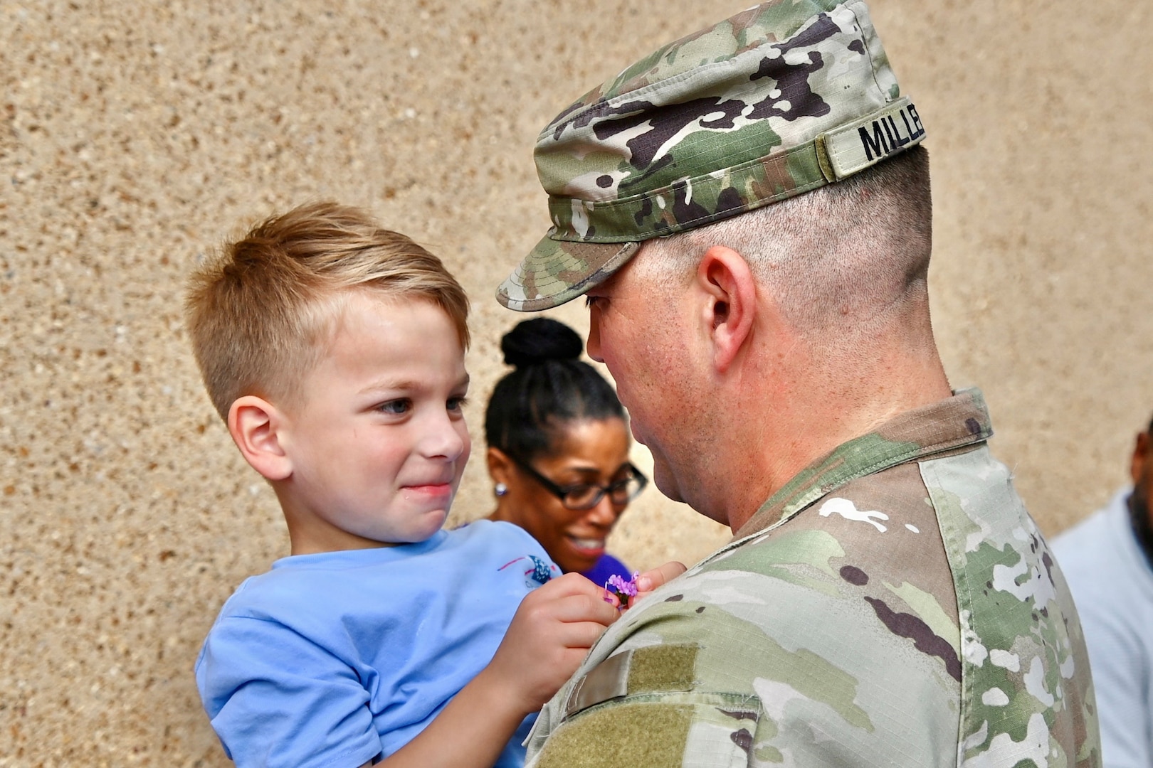 Soldier father holds his son while taking to him.