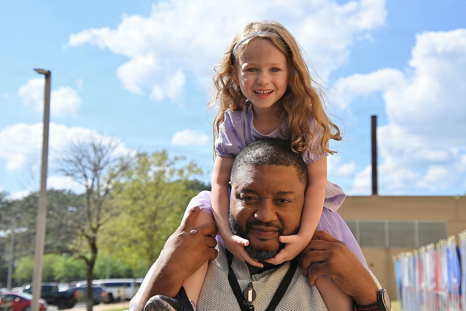 Father posing with daughter perched on his shoulders.
