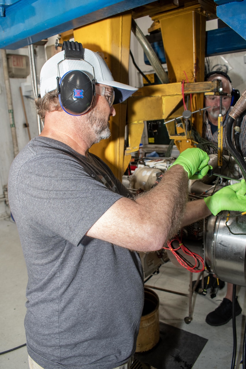 Grady Mayo, an artisan in the Fleet Readiness Center East Engine Driven Compressor and Gas Turbine Compressor Shop, connects a C-2A Greyhound auxiliary power unit to a test stand in order to check the component’s functionality.