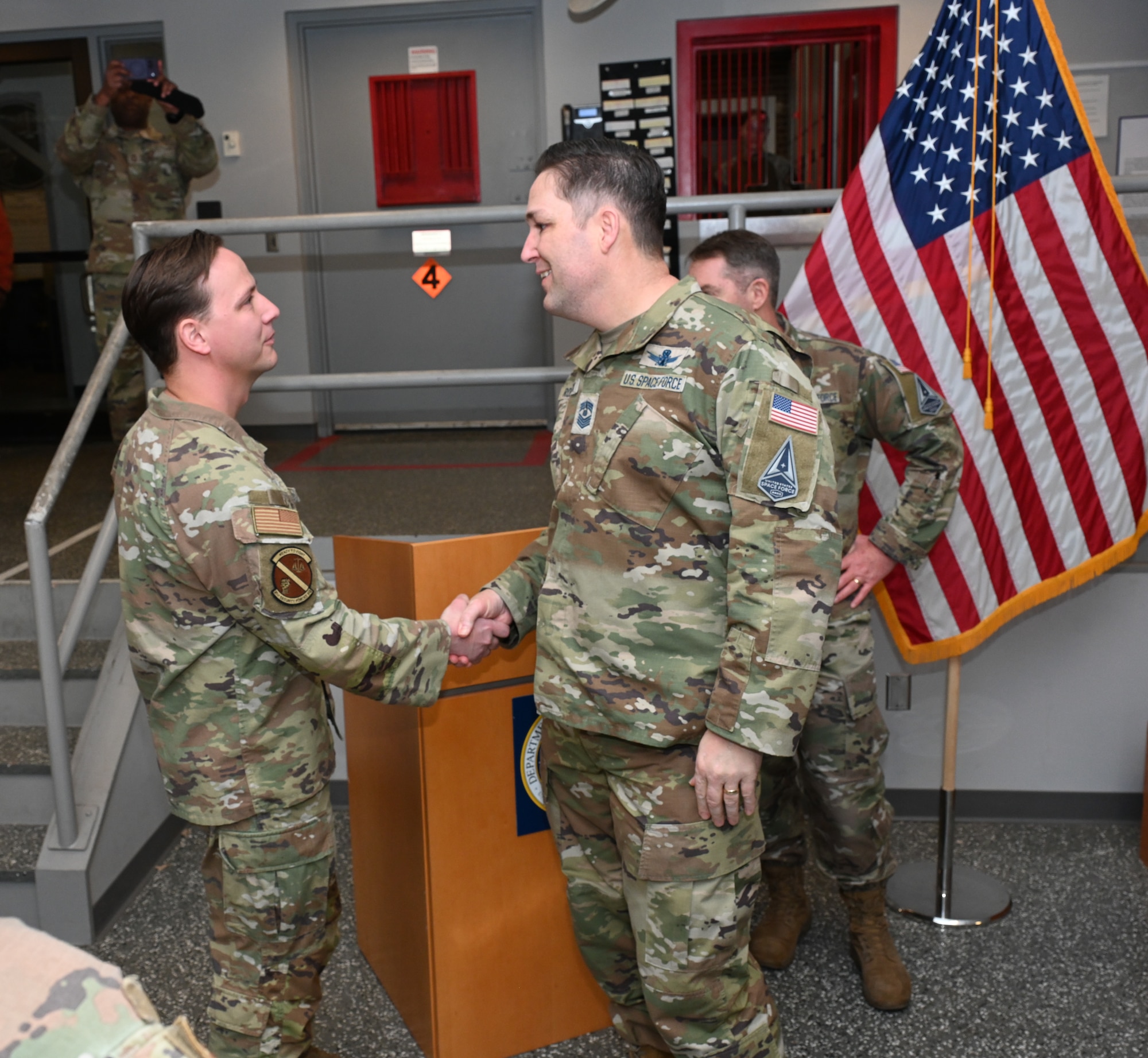 U.S. Space Force Chief Master Sgt. Micheal Rozneck gives a handshake to U.S. Air Force Staff Sgt. Adam Sullivan.