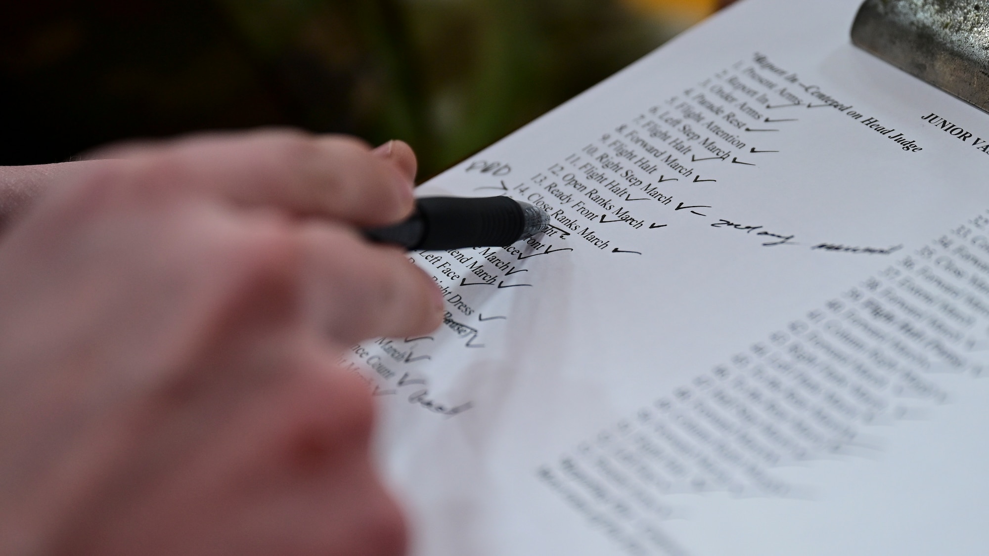 An Air Force Junior Reserve Officer Training Corps judge points at a drill movement in a list of movements.