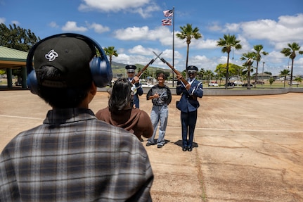 Kapolei High School students take turns posing with U.S. Air Force Senior Airman Zephrendae Buford, left, and Airman 1st Class Malik Price, right, both ceremonial guardsmen with the U.S. Air Force Honor Guard in Kapolei, Hawaii, March 30, 2026. The drill team members spoke on their active-duty military experiences and took photos with the spectators following the drill team performance. (U.S. Air Force photo by Staff Sgt. Jordan Powell)