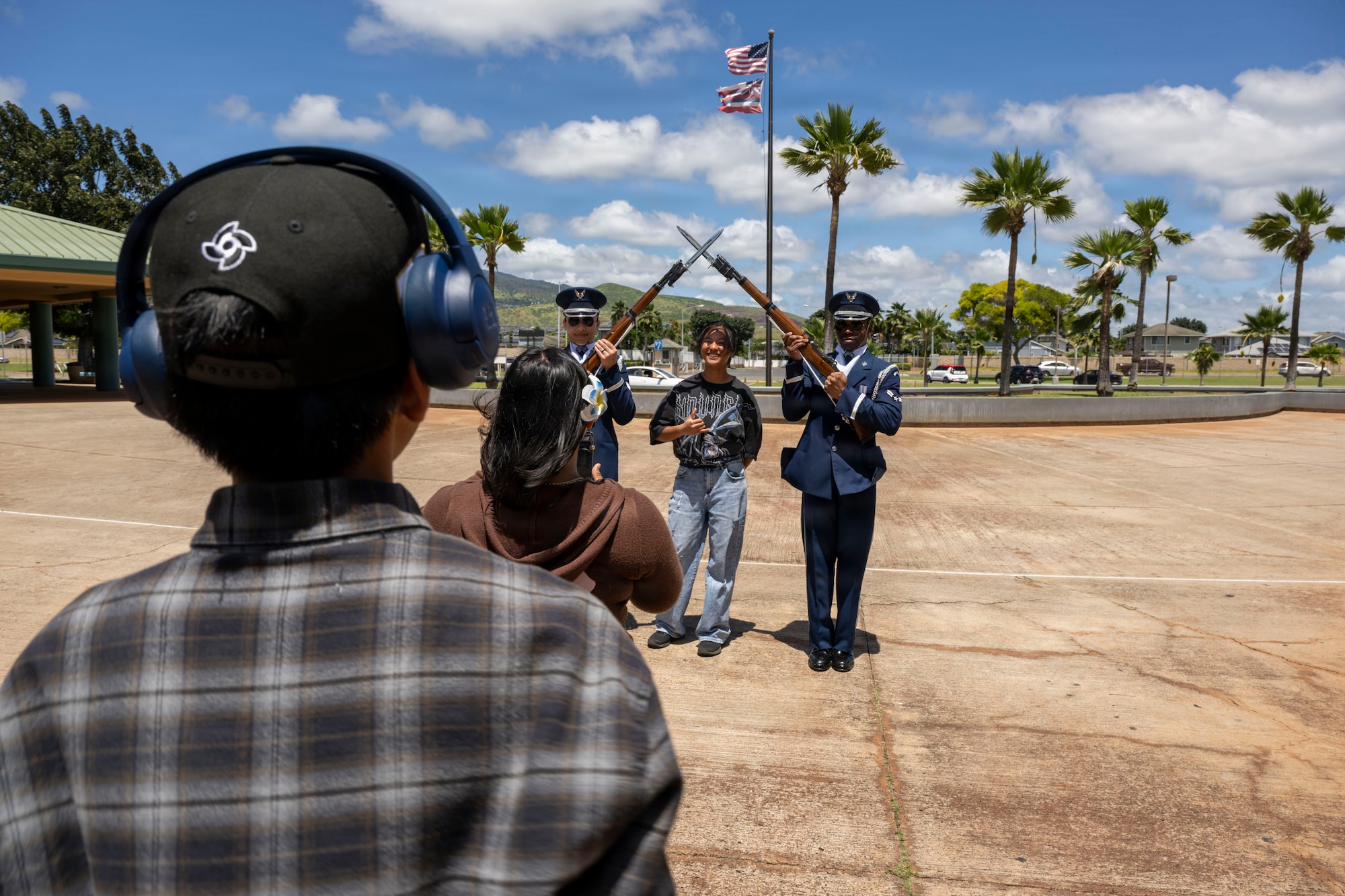 Kapolei High School students take turns posing with U.S. Air Force Senior Airman Zephrendae Buford, left, and Airman 1st Class Malik Price, right, both ceremonial guardsmen with the U.S. Air Force Honor Guard in Kapolei, Hawaii, March 30, 2026. The drill team members spoke on their active-duty military experiences and took photos with the spectators following the drill team performance. (U.S. Air Force photo by Staff Sgt. Jordan Powell)
