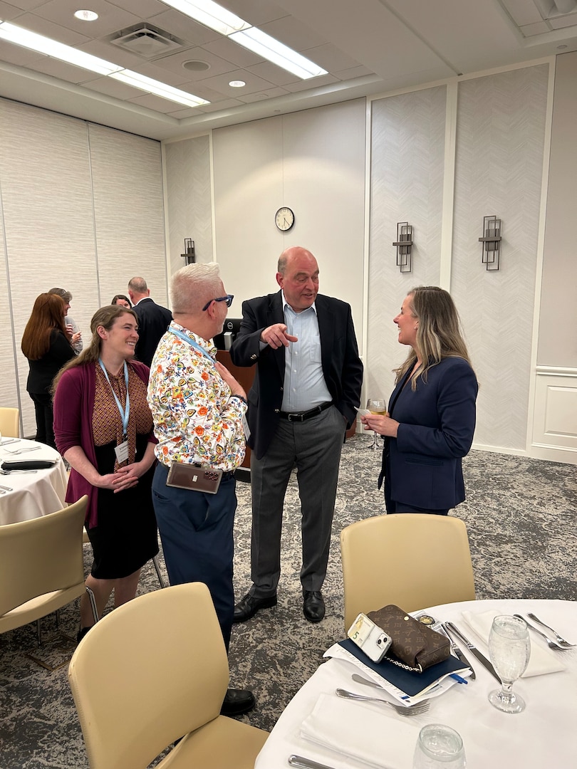 Three people stand near a table talking