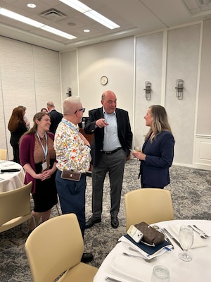 Three people stand near a table talking