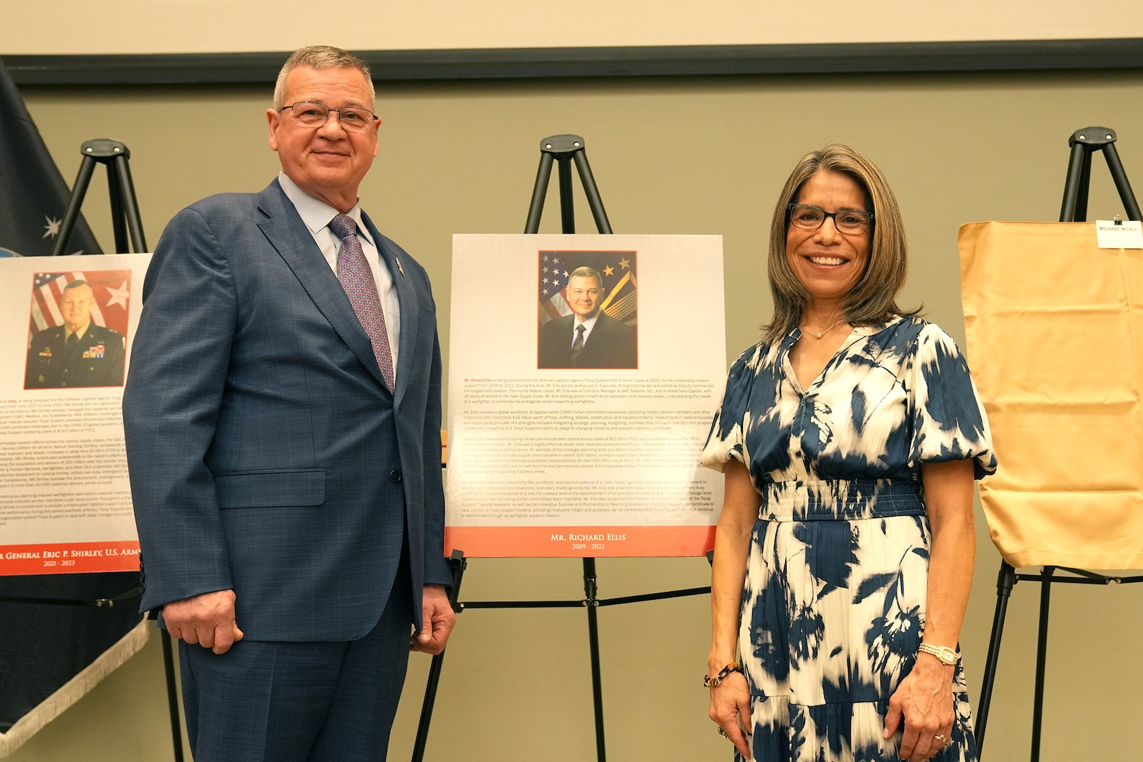man and woman stand on stage next to plaque