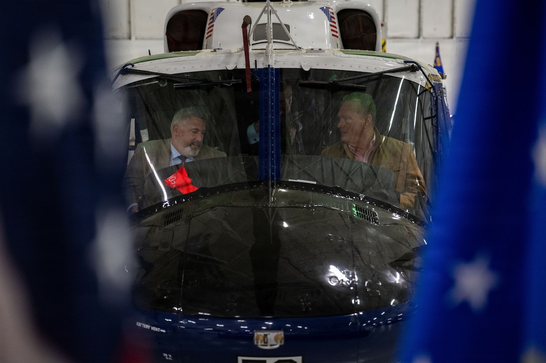 Matthew Lemire, and Douglas Plain, sit in a UH-1N Huey during the 2026 Honorary Commander Induction Ceremony.
