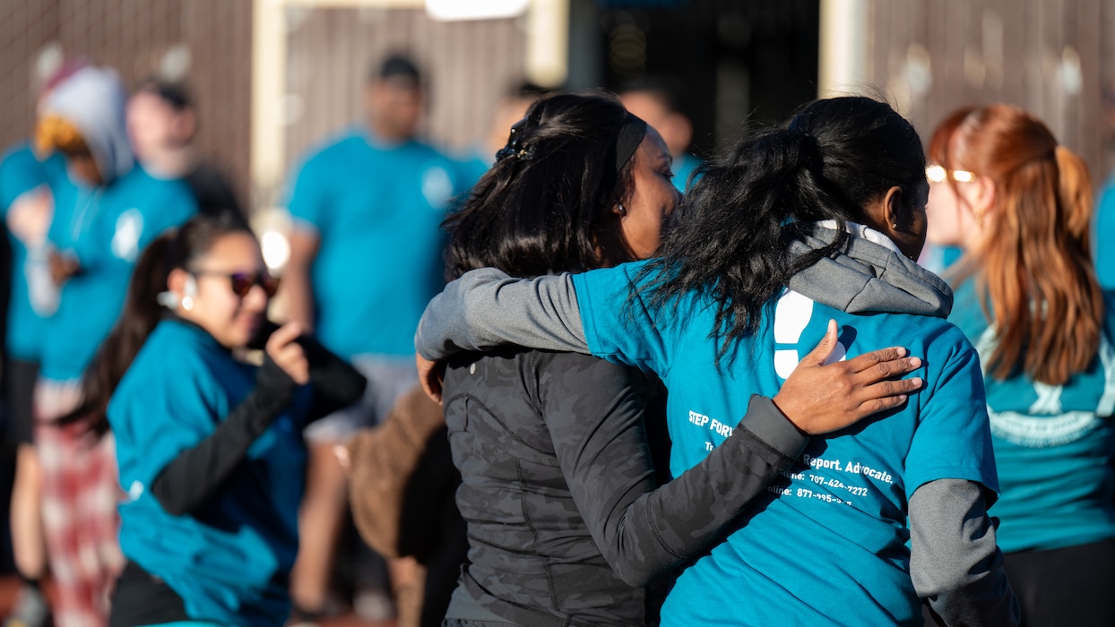 Two Airmen embrace each other with their backs to the viewer